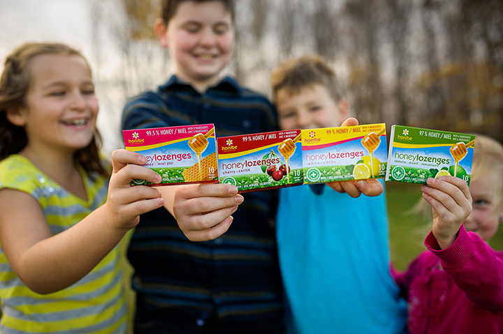 Four kids each holding a box of honey lozenges