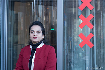 Anila Noor, posant devant les portes tournantes d’un bâtiment.