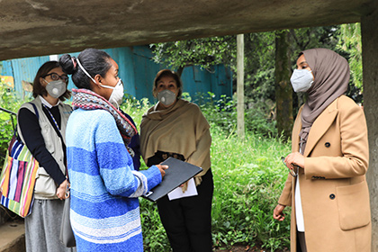 Four women wearing protective masks meet outside to discuss the needs of women and children in Ethiopia.