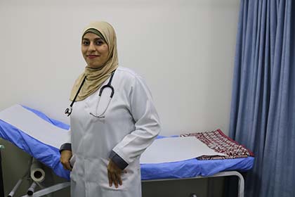 Une femme portant une blouse de laboratoire médical se tient devant une table d'examen médical.