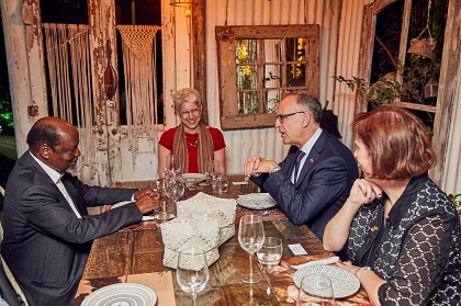 Isabelle Bérard, souriante, est assise autour d'une table avec deux hommes et une femme.