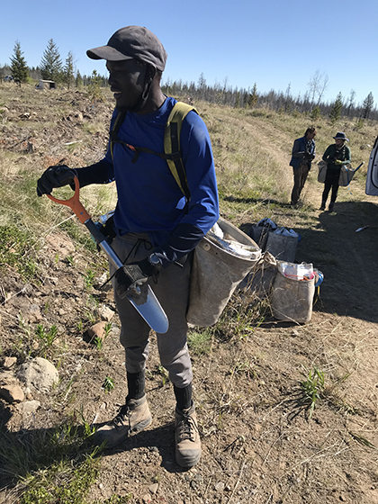 A man stands in a field holding a shovel.