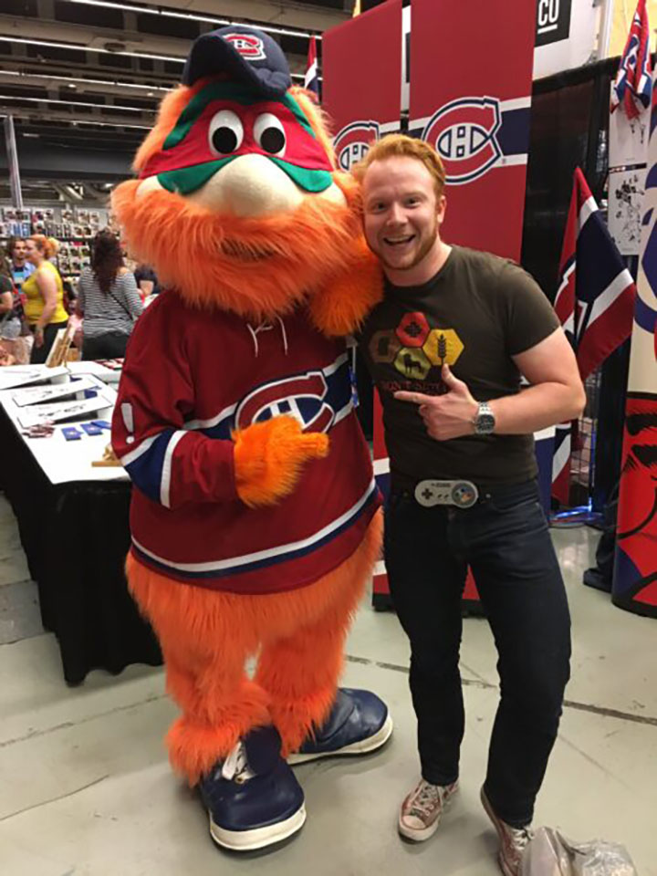 Homme debout avec la mascotte d'une équipe de hockey
