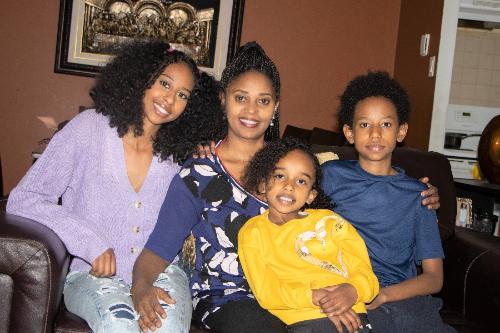 A woman smiling and sitting with her 3 children.