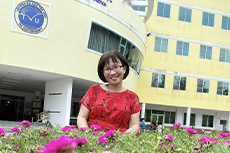 Tieu Thanh Thuy posing in front of a Tra Vinh University building.