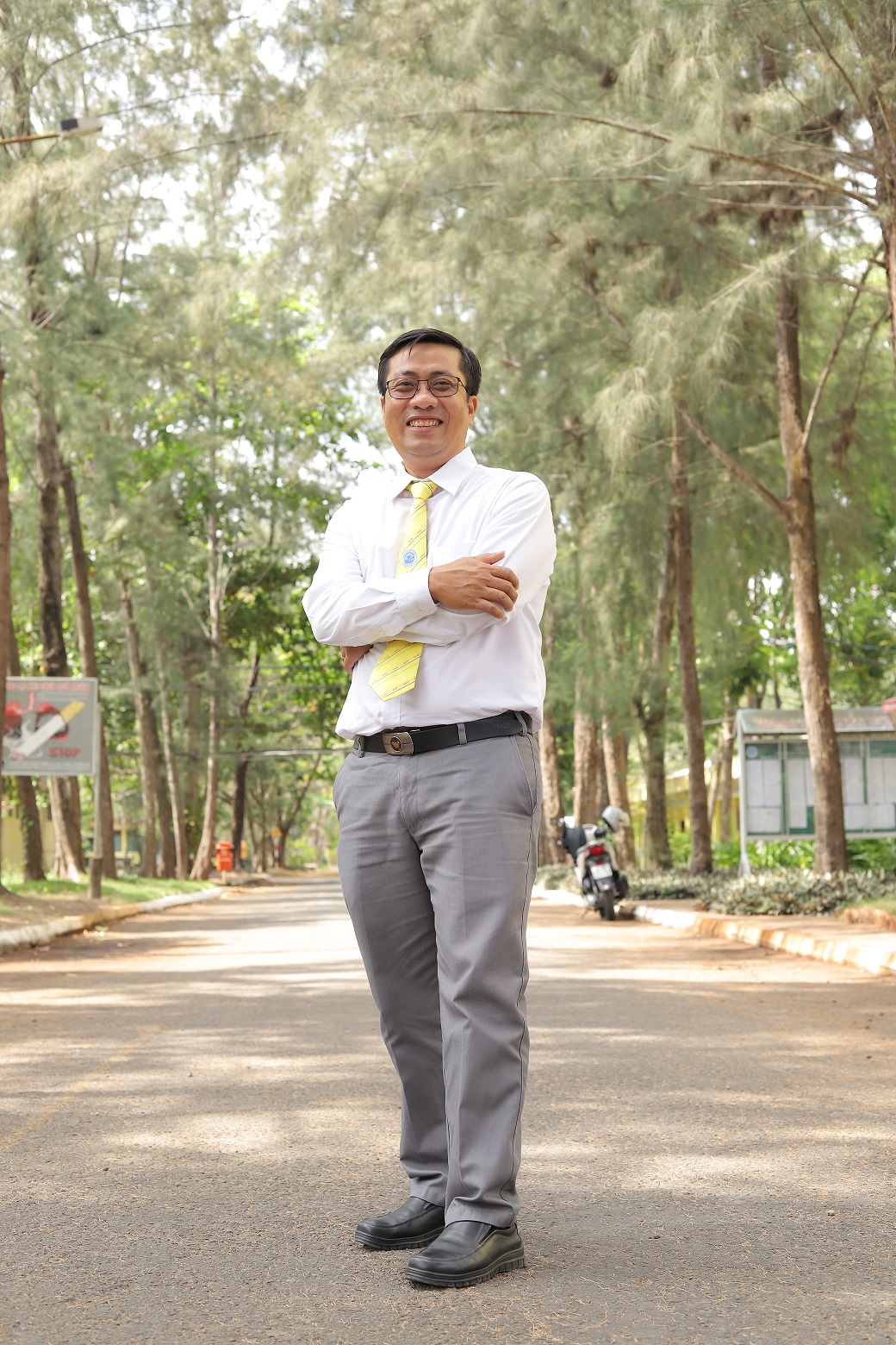 Nguyen Minh Trung stands on a road between two rows of trees.