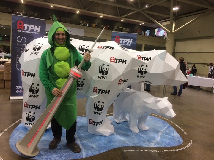 Man dressed as a green bean holding a CN Tower model standing in front of two polar bear statues