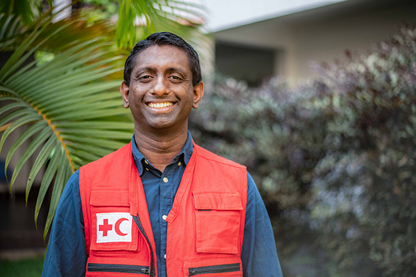 Chiran Livera sourit à l’appareil photo en portant un gilet de la Fédération internationale des Sociétés de la Croix-Rouge et du Croissant-Rouge