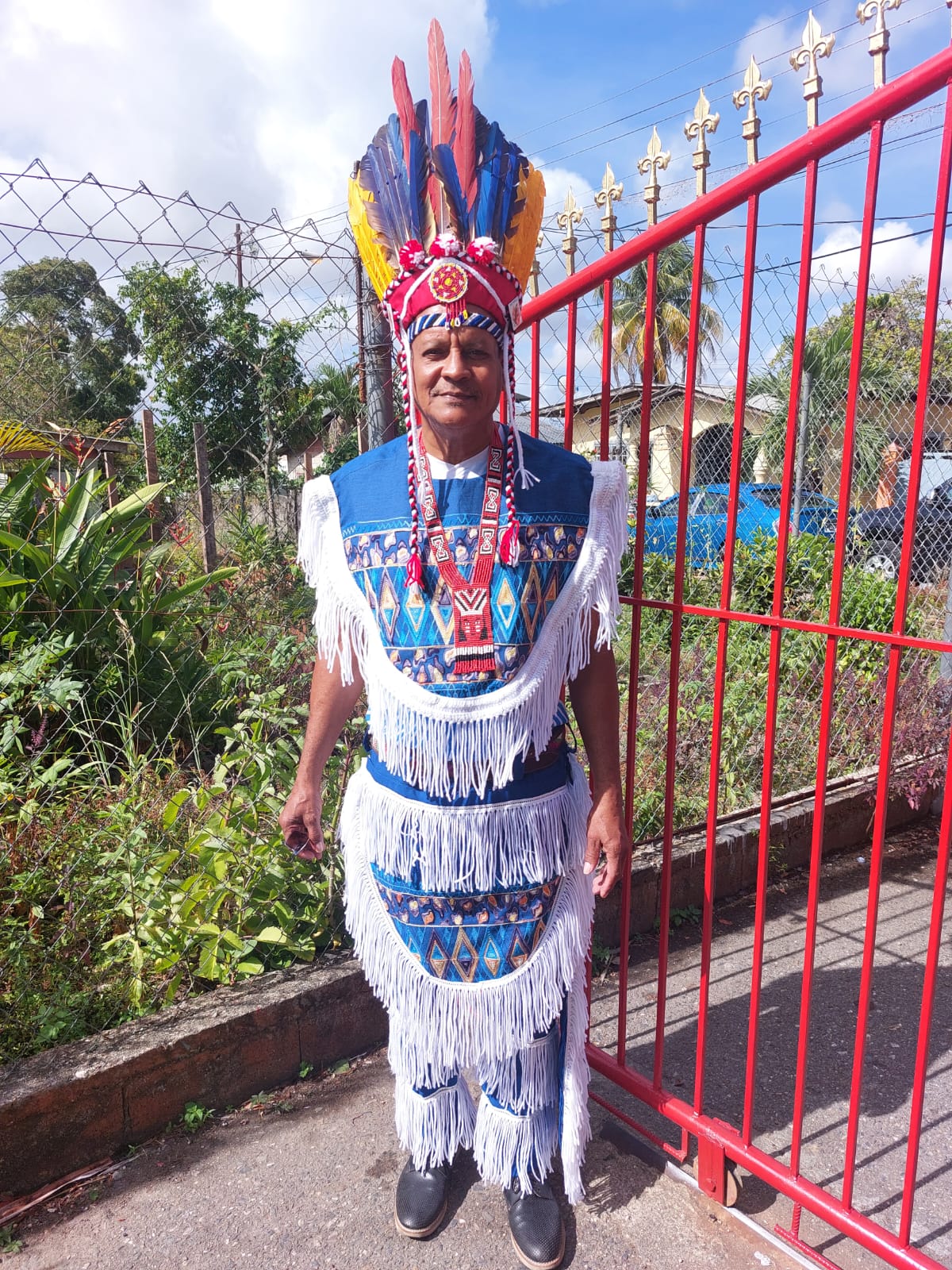Ricardo Bharath Hernandez, dressed in traditional Indigenous regalia, smiles at the camera