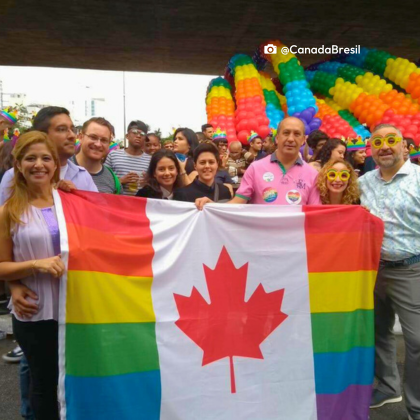 Le personnel de l'ambassade du Canada fête la saison des fiertés au Brésil. Les employés sont vêtus de couleurs vives et tiennent un drapeau arc-en-ciel du Canada lors de la parade de la Fierté à São Paulo.