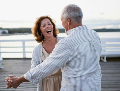 An elderly couple dancing on a waterfront terrace