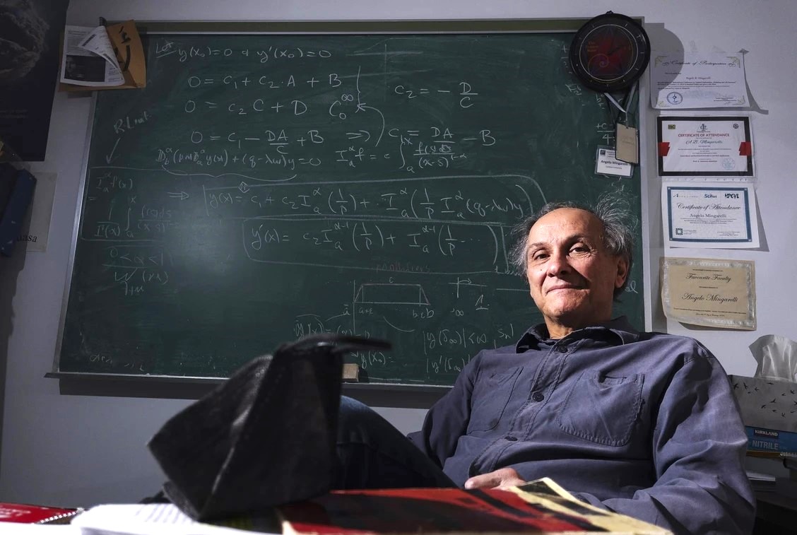 A man sits in front of a blackboard.