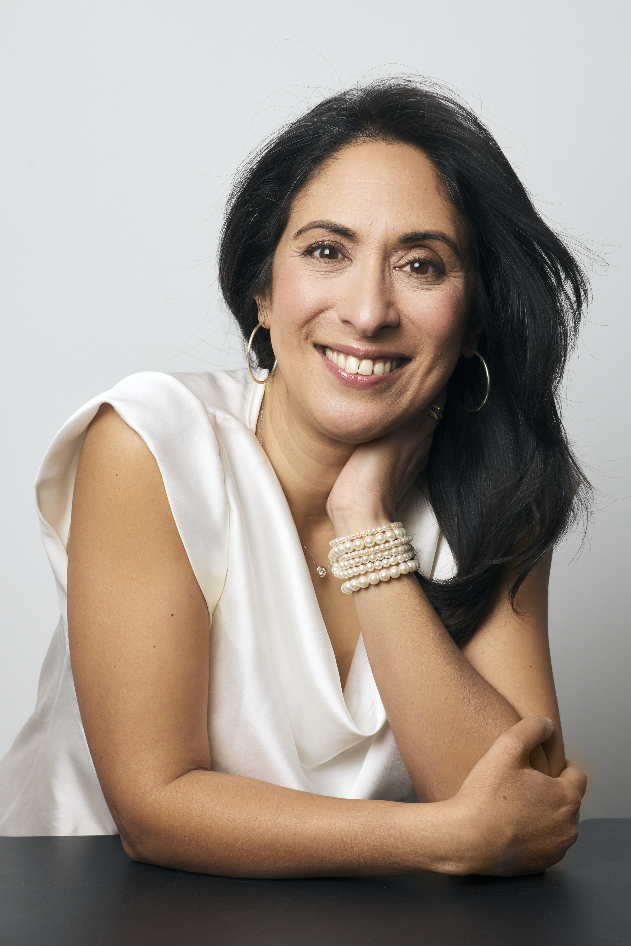 A woman wearing a white blouse smiles at the camera