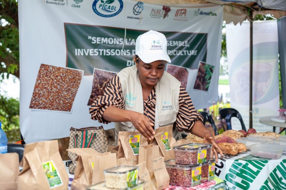 A woman stands in front of a booth, arranging bags and containers of beans