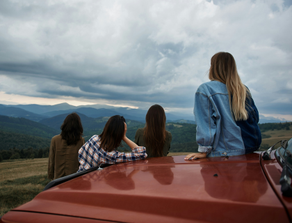 Groupe de jeunes voyageuses à côté de leur voiture regardant les montagnes